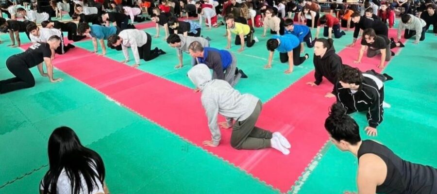 Sala de gimnasio donde se lleva a cabo un evento: los niños participantes realizan un ejercicio